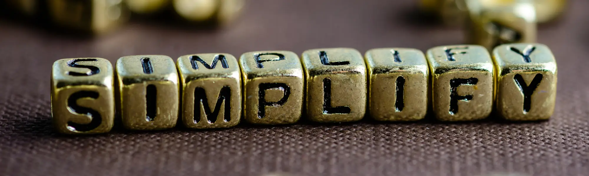 The word "simplified" carved into small wooden cubes. Because good leadership development can be found by simplifying the process!